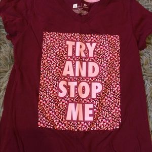 Magenta shirt with TRY AND STOP me written on it.